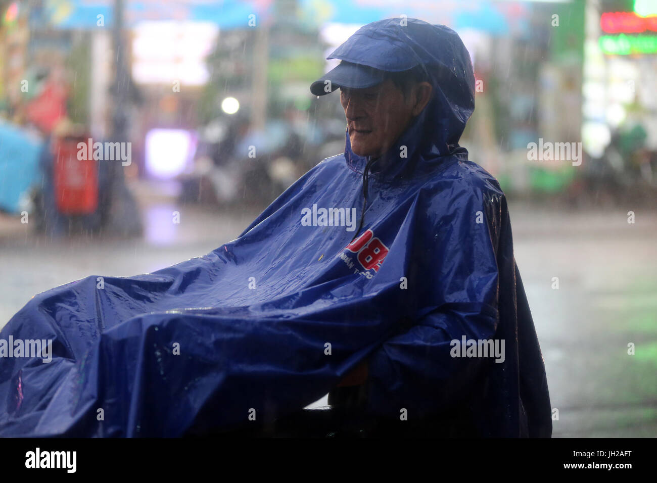 Heavy monsoon rain. Motor Scooter on Saigon Street. Vietnam. Stock Photo