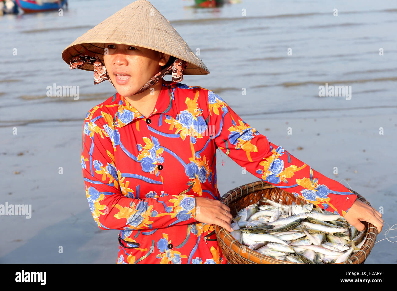 Vung Tau beach. Fishing boats. Woman sorting fishing catch.  Vietnam. Stock Photo