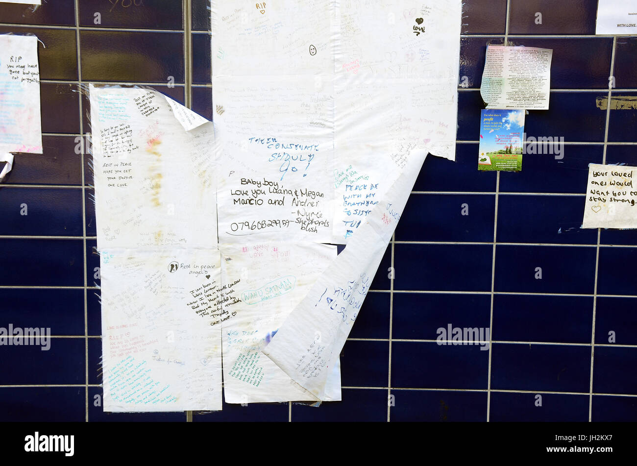 London, UK, 12/07/2017 Flowers, tributes and missing person posters show signs of weather deterioration but remain near Grenfell Tower one month after  fire in which many people died. Stock Photo