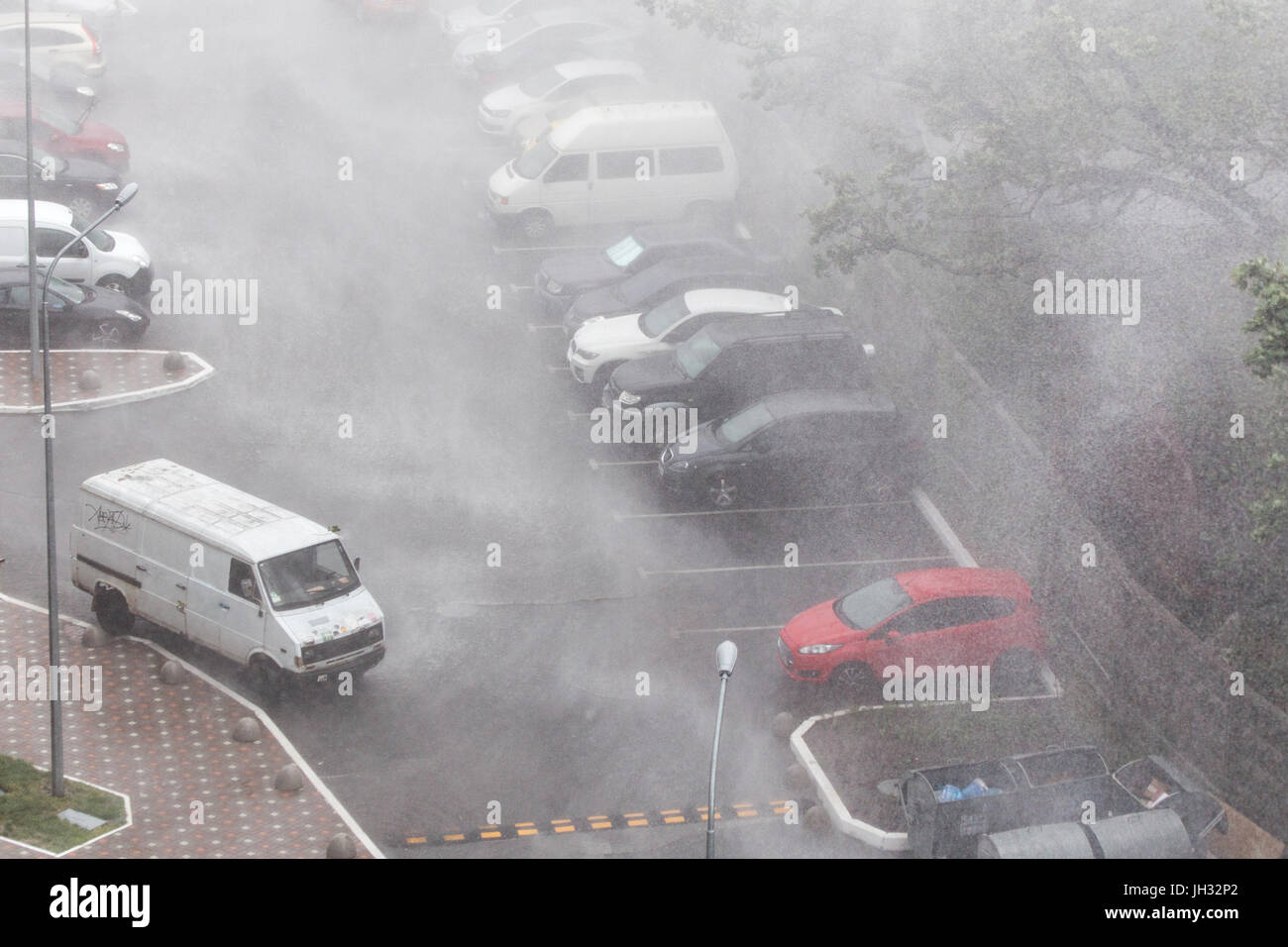 Cars parked at a parking lots near highrise building under heavy