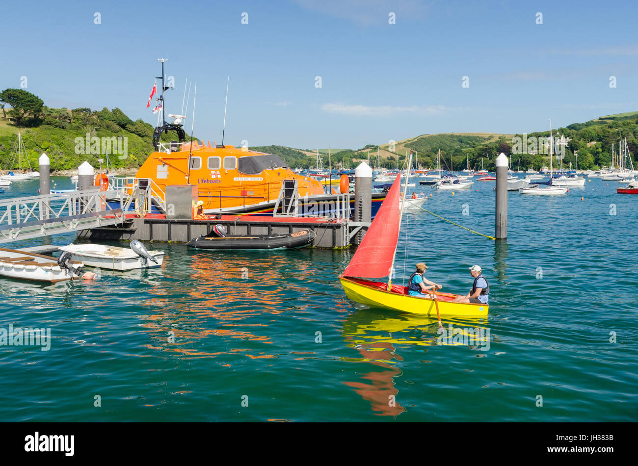 Brightly coloured sailing dinghy in the water in the Salcombe estuary Stock Photo