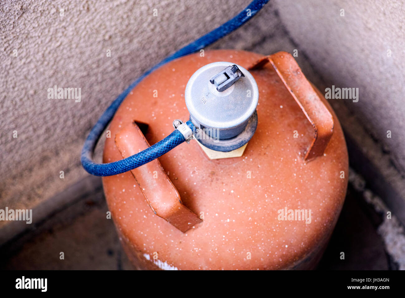 Orange gas bottle with gas regulator stay in corner Stock Photo Alamy