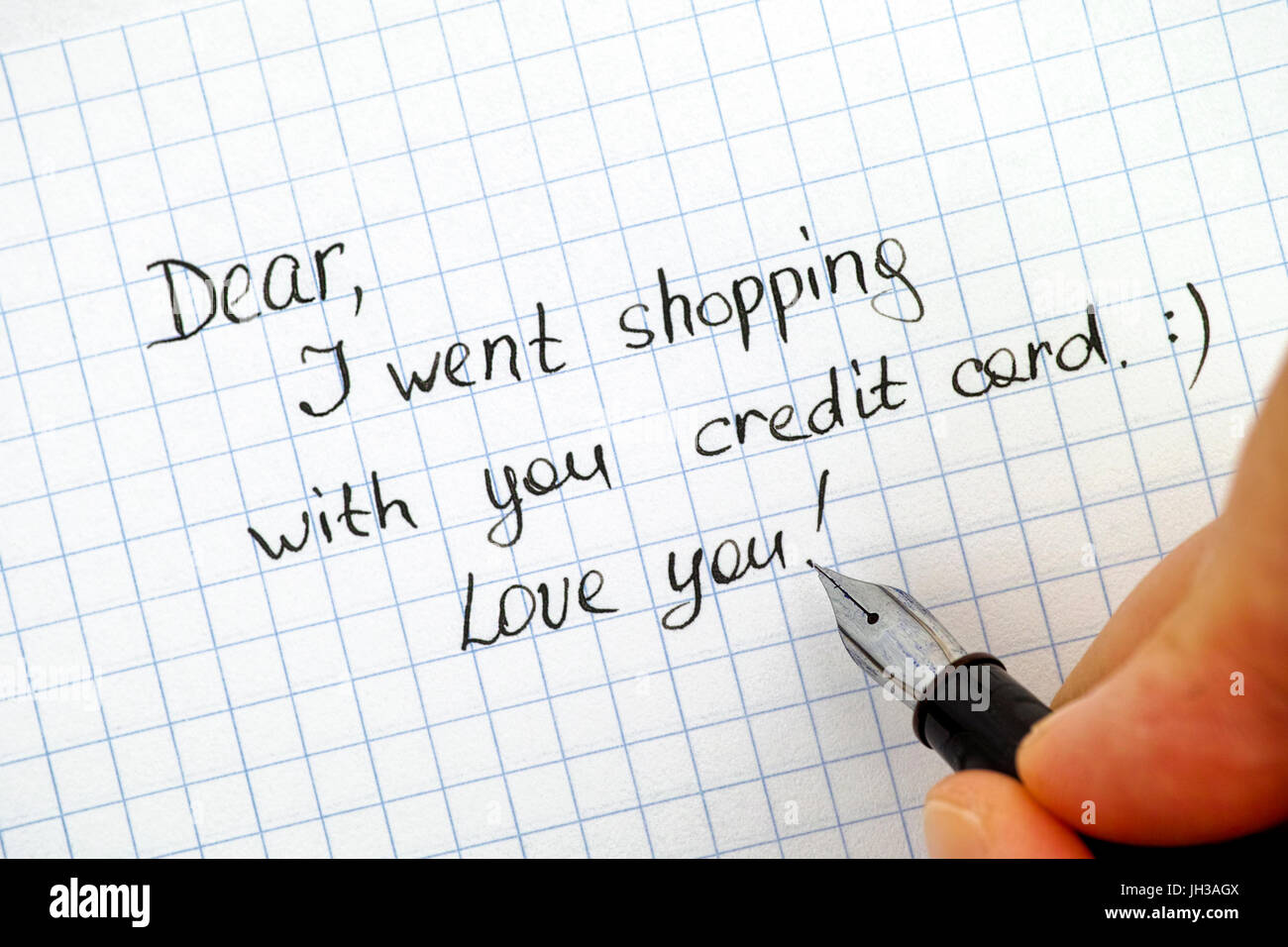 Woman hand with pen wriring note - Dear, I went shopping with  your credit card. Love you! Stock Photo