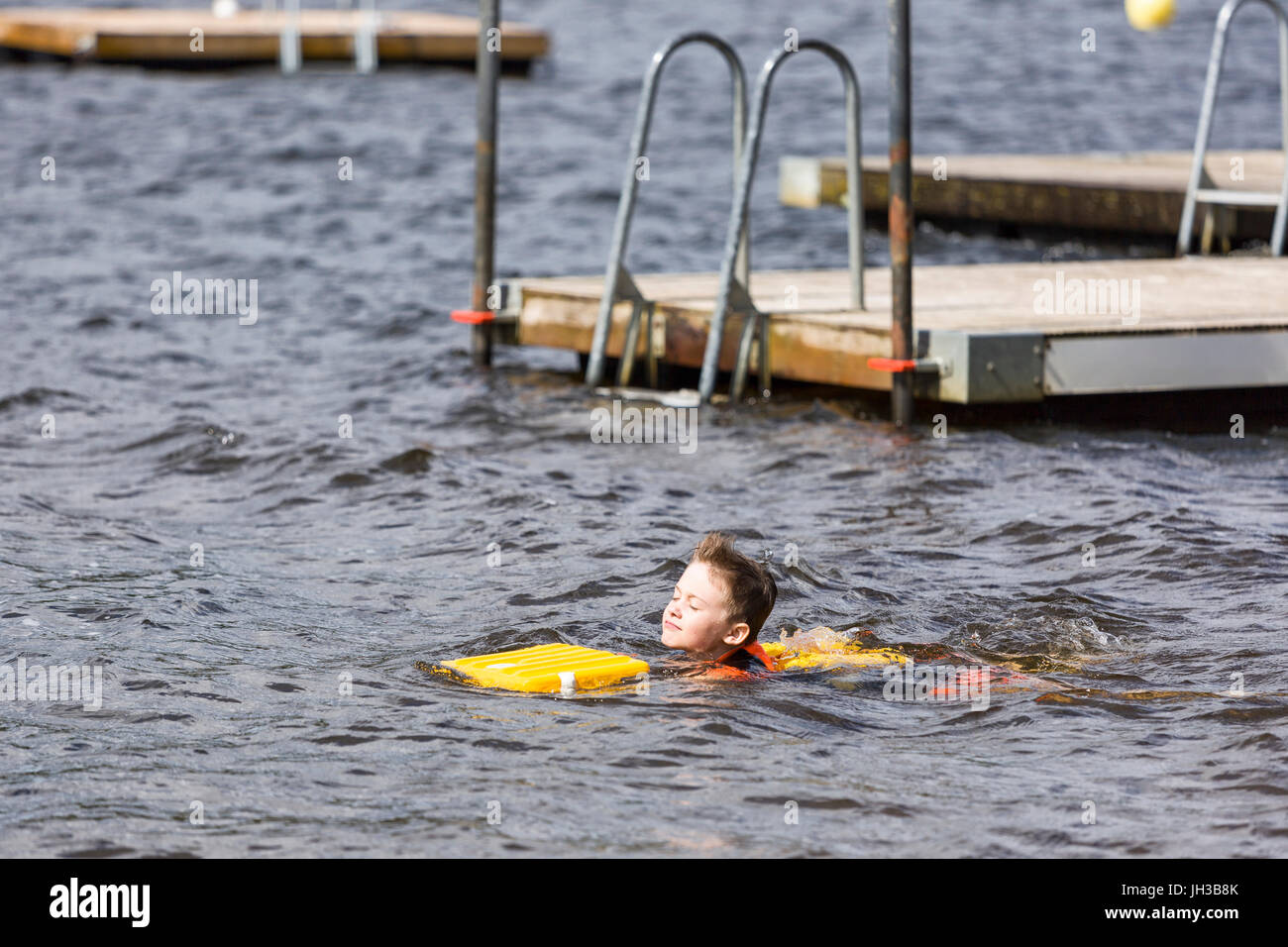 Young caucasian boy learning to swim using buoyancy aids at swimming