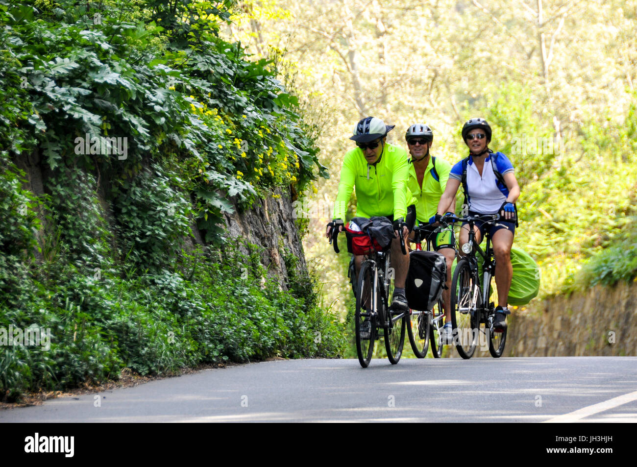 Three touring cyclists riding their bicycles on a country road in Calabria, Italy. Stock Photo