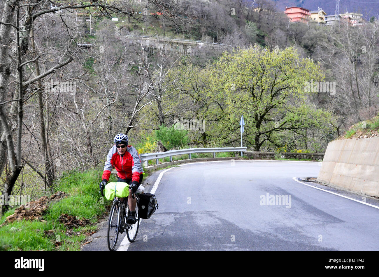 A touring cyclist riding his bicycle on a country road in Calabria, Italy. Stock Photo
