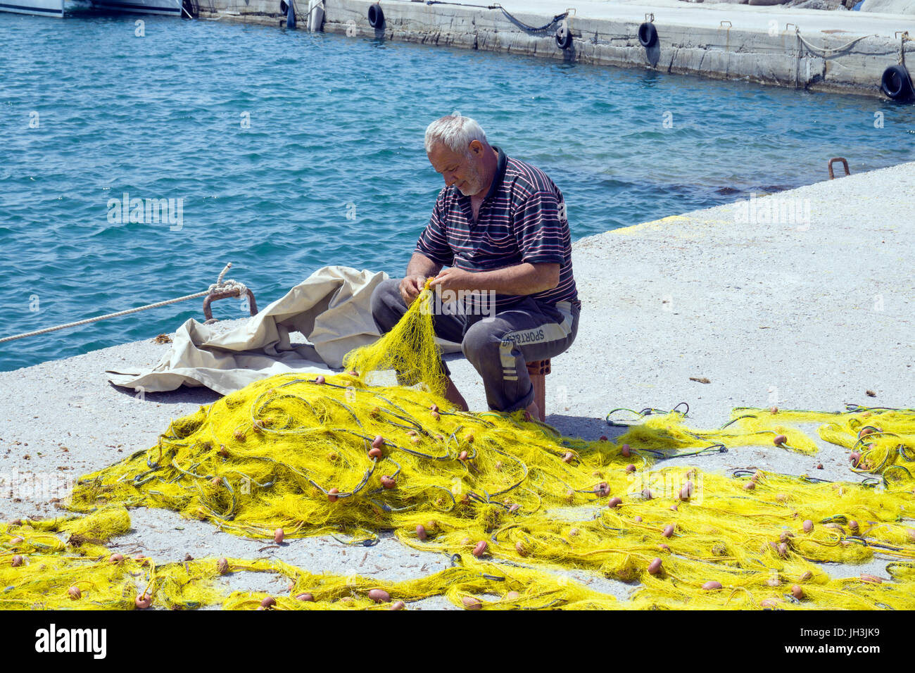 Fischer repariert Netze im Hafen von Vilchada, Santorin, Kykladen, Aegaeis, Griechenland, Mittelmeer, Europa | Fisherman repairs nets at the harbour o Stock Photo