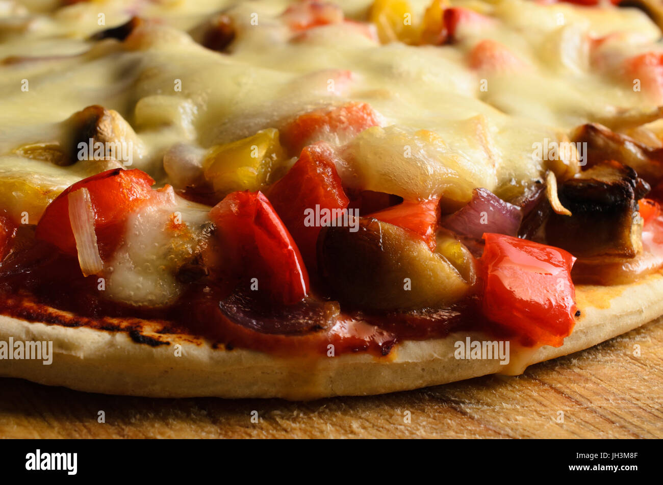 Close up (macro) of a cooked vegetarian pizza, with red and yellow peppers, onions, mushrooms and mozzarella cheese. Stock Photo