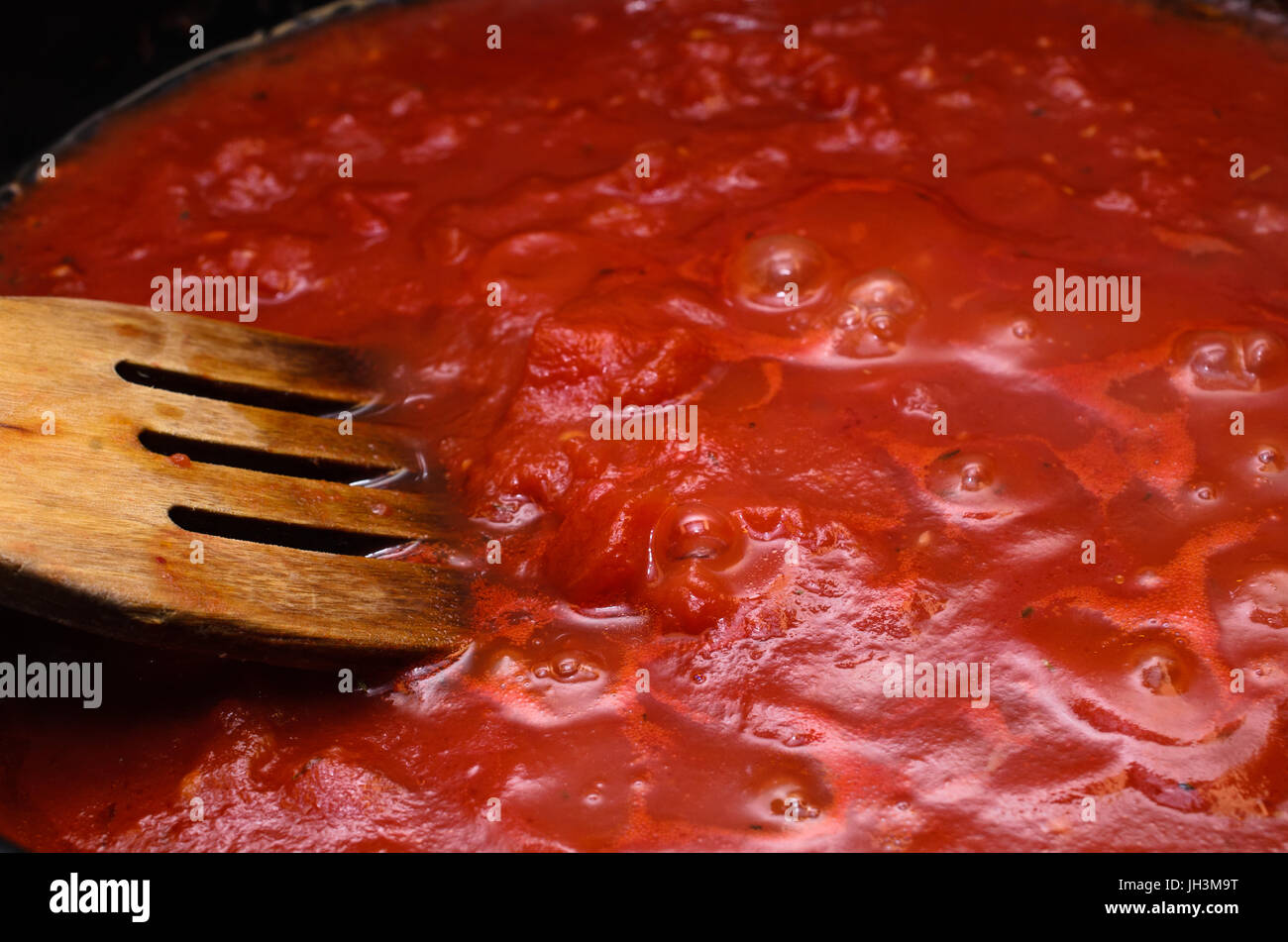 Bubbling hot tomato sauce for pasta, cooking in pan with wooden spatula. Stock Photo
