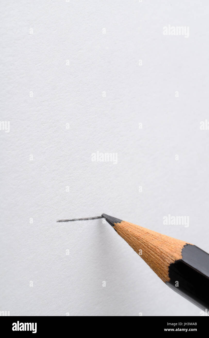 A graphite pencil drawing a line across a blank white page.  Copy space above. Stock Photo