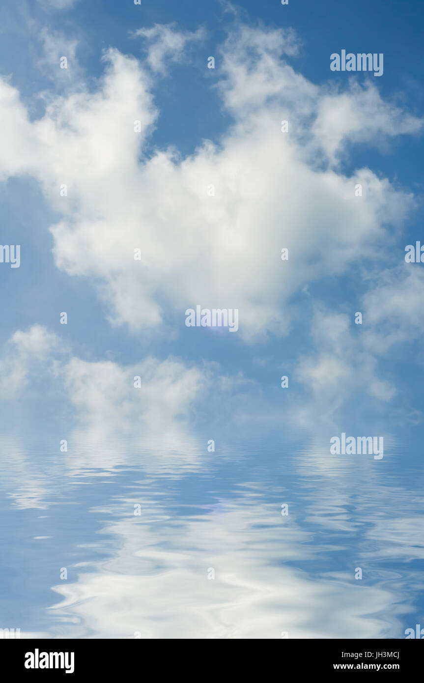 Fluffy white clouds in bright blue sky, reflected in clear rippling sea or lake below horizon. The sky is  photographed, with water added artificially Stock Photo