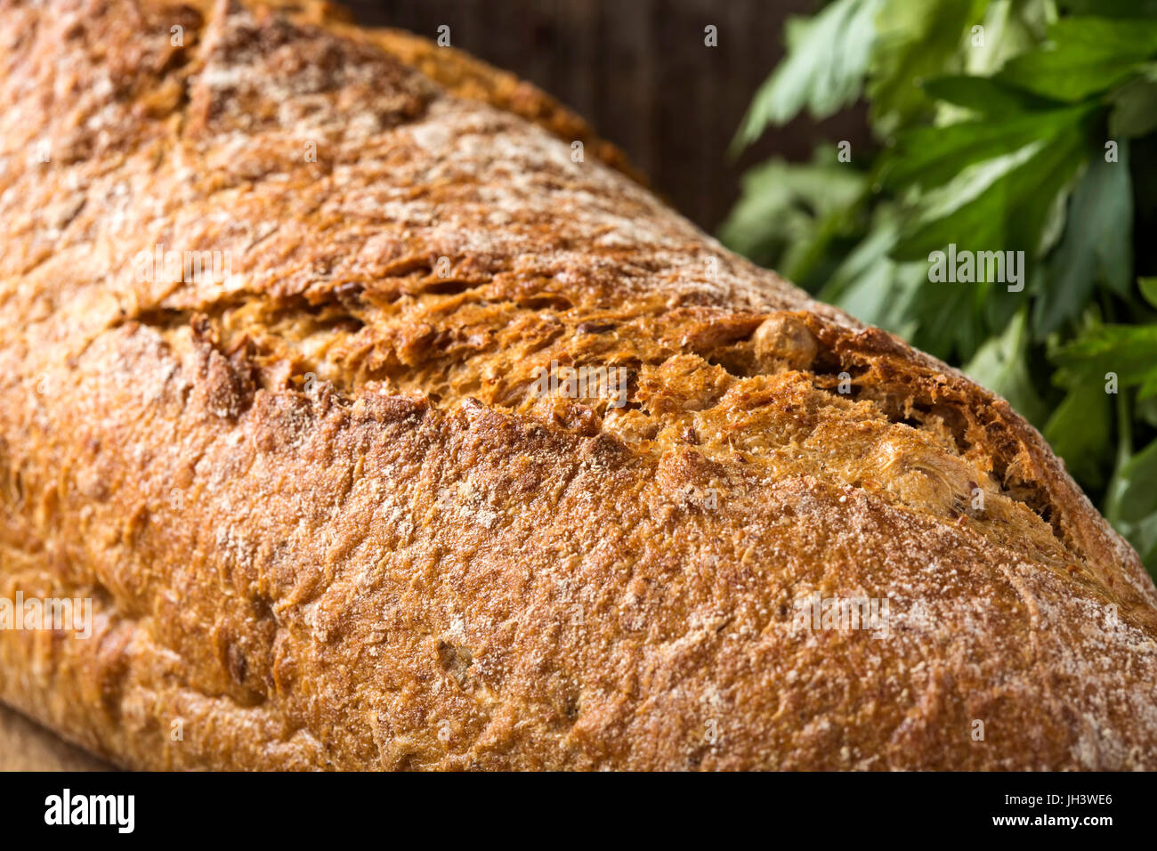 Close-up of freshly baked homemade bread and parsley bunch in background Stock Photo