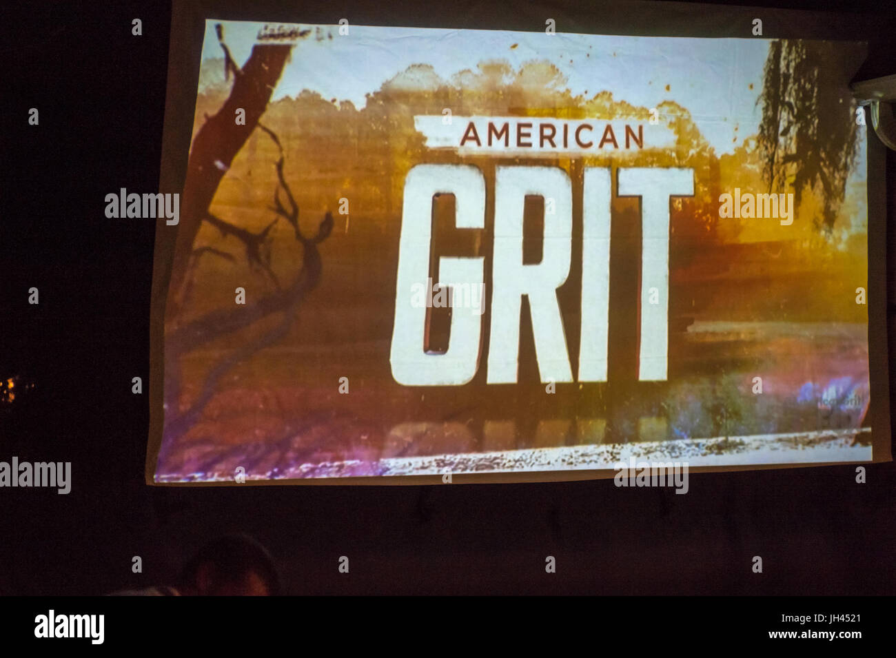 Merrick, New York, USA. 11th June 2017.  In backyard of 'American Grit' contestant Chris Edom, the American Grit logo appears on large screen that sho Stock Photo