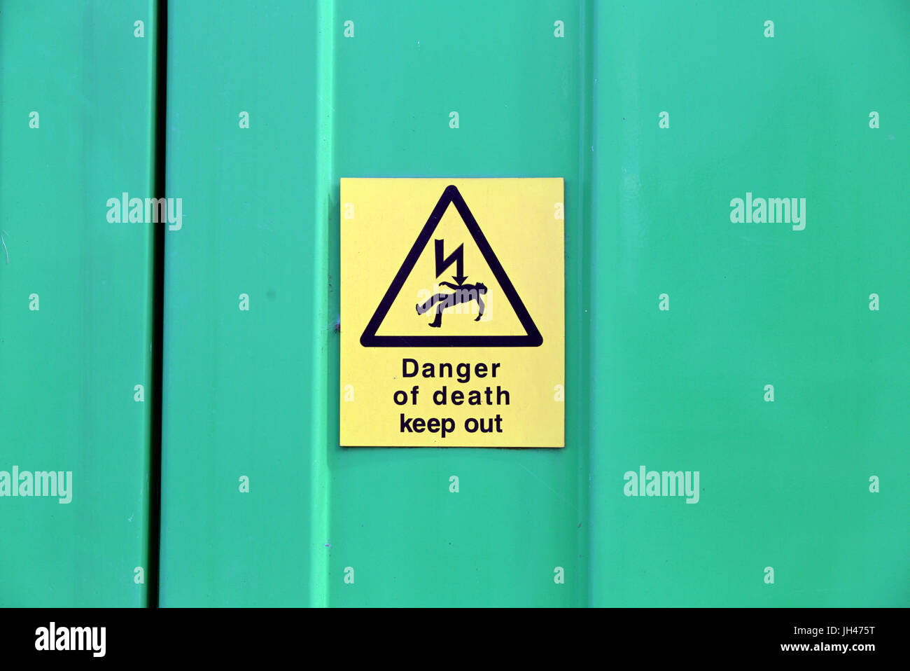 danger of death electrical yellow sign on green steel wall Stock Photo