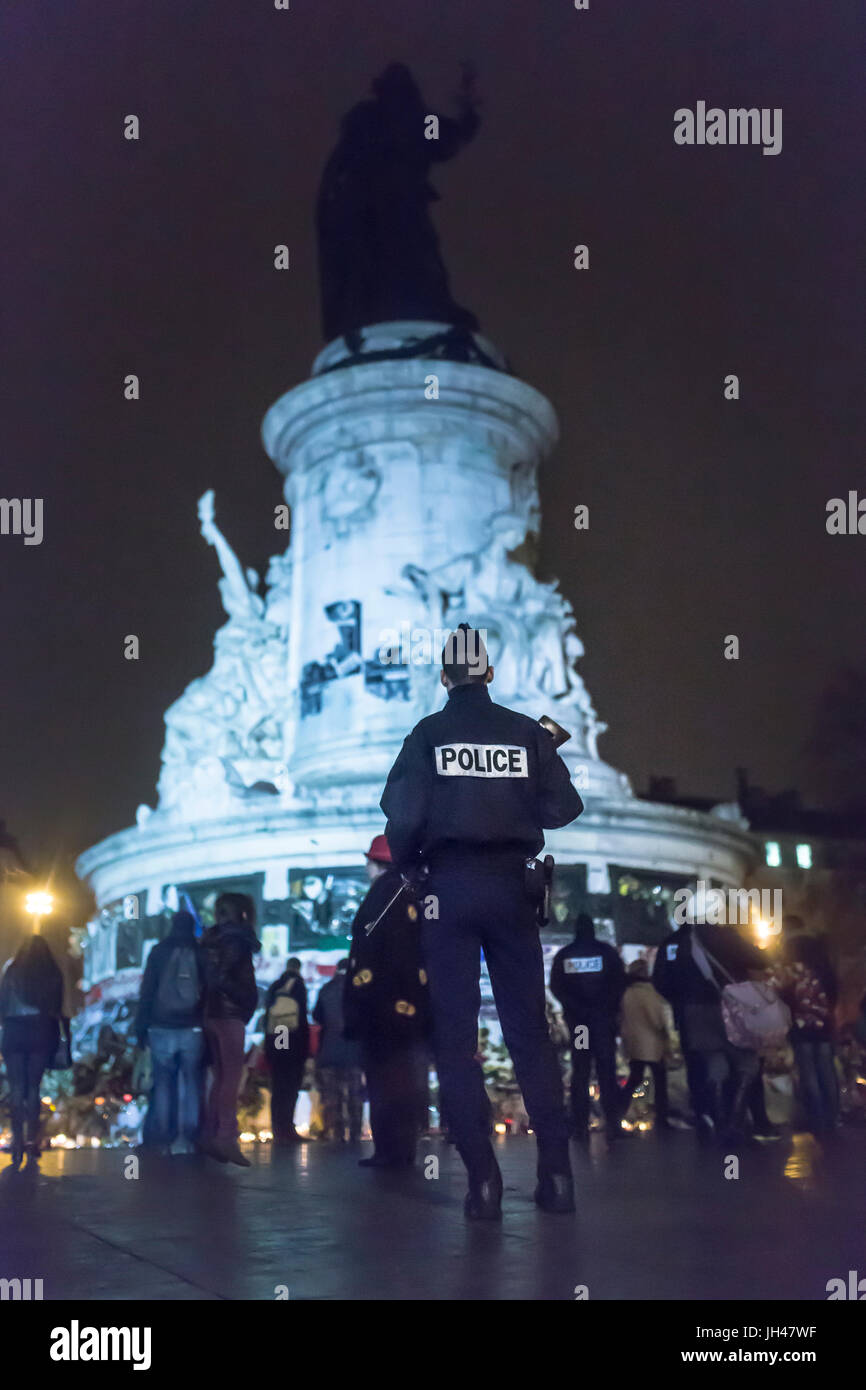 A policeman standing in front of the statue of la republique. Homage at the victims of the terrorist attacks in Paris the 13th of november 2015. Stock Photo