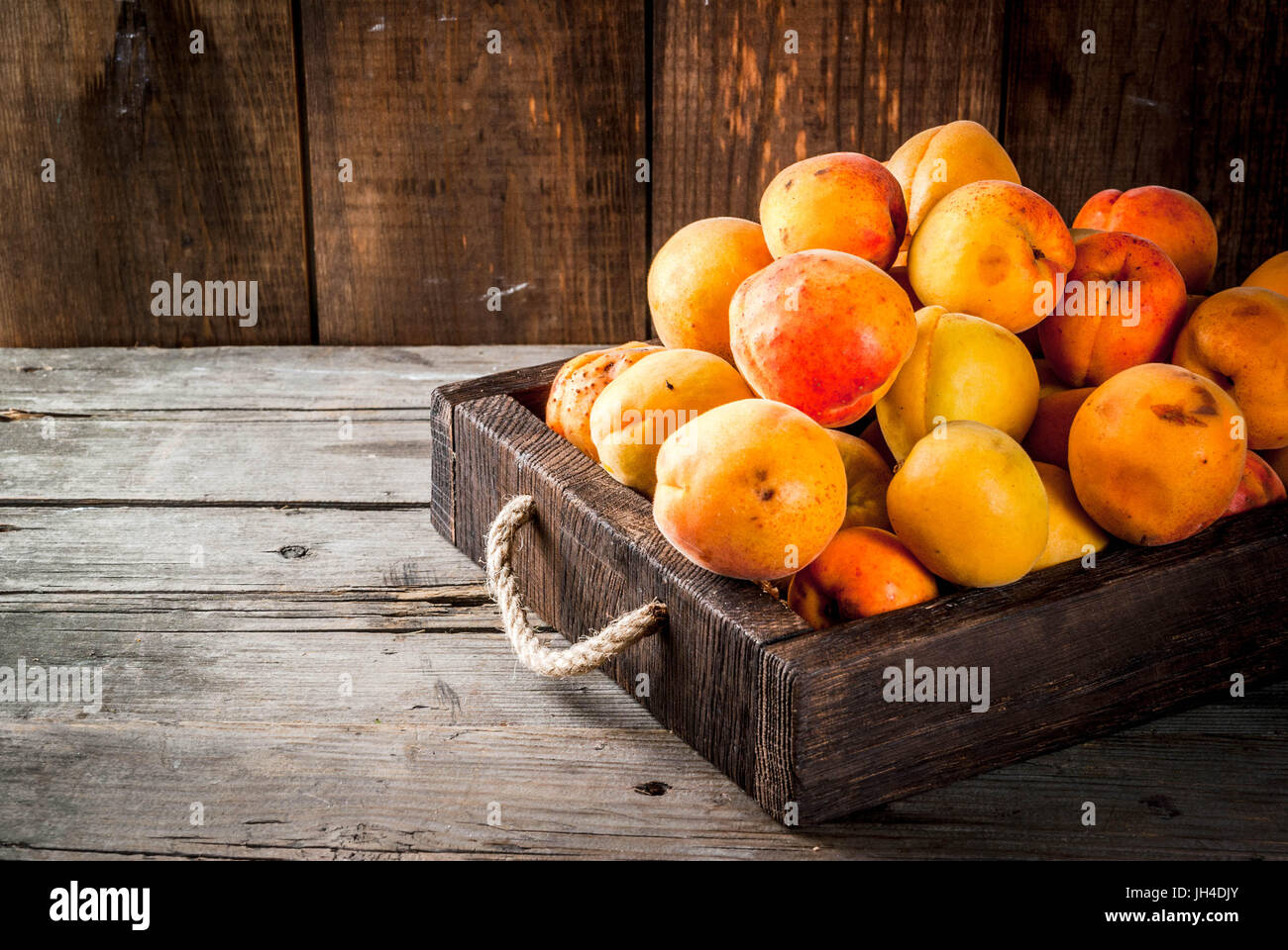 Summer fruits. Fresh raw organic farm apricots in a wooden box, a tray ...
