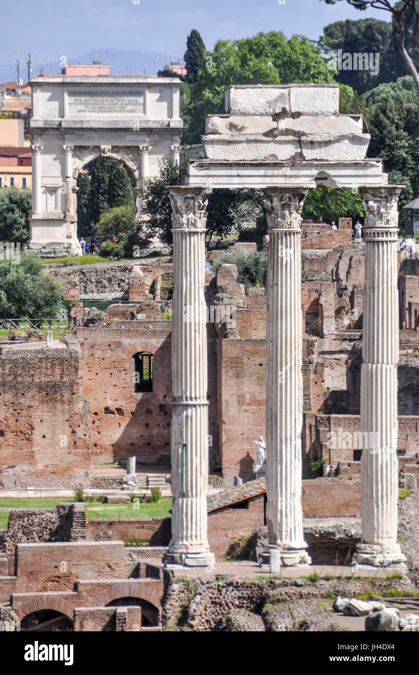 The ruins of the Temple of Castor and Pollux and the Arch of Titus behind at the Roman Forum, Rome, Italy. Stock Photo