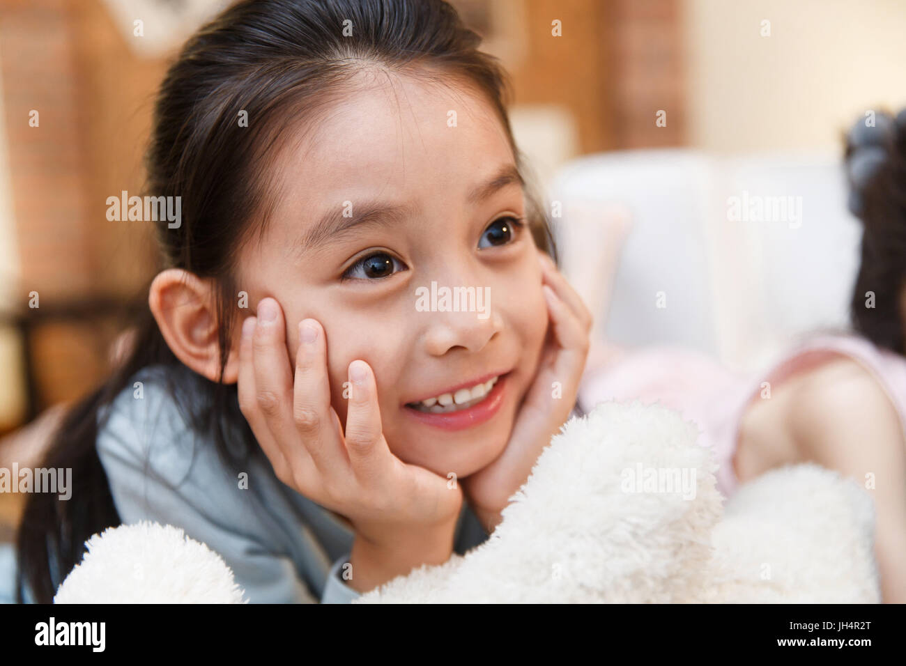 Happy girl lying on floor with hands on chin Stock Photo - Alamy