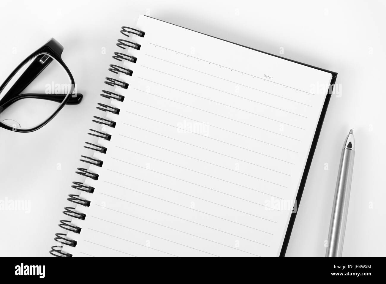 Top view of blank notepad with black eyeglasses and pen on white background Stock Photo