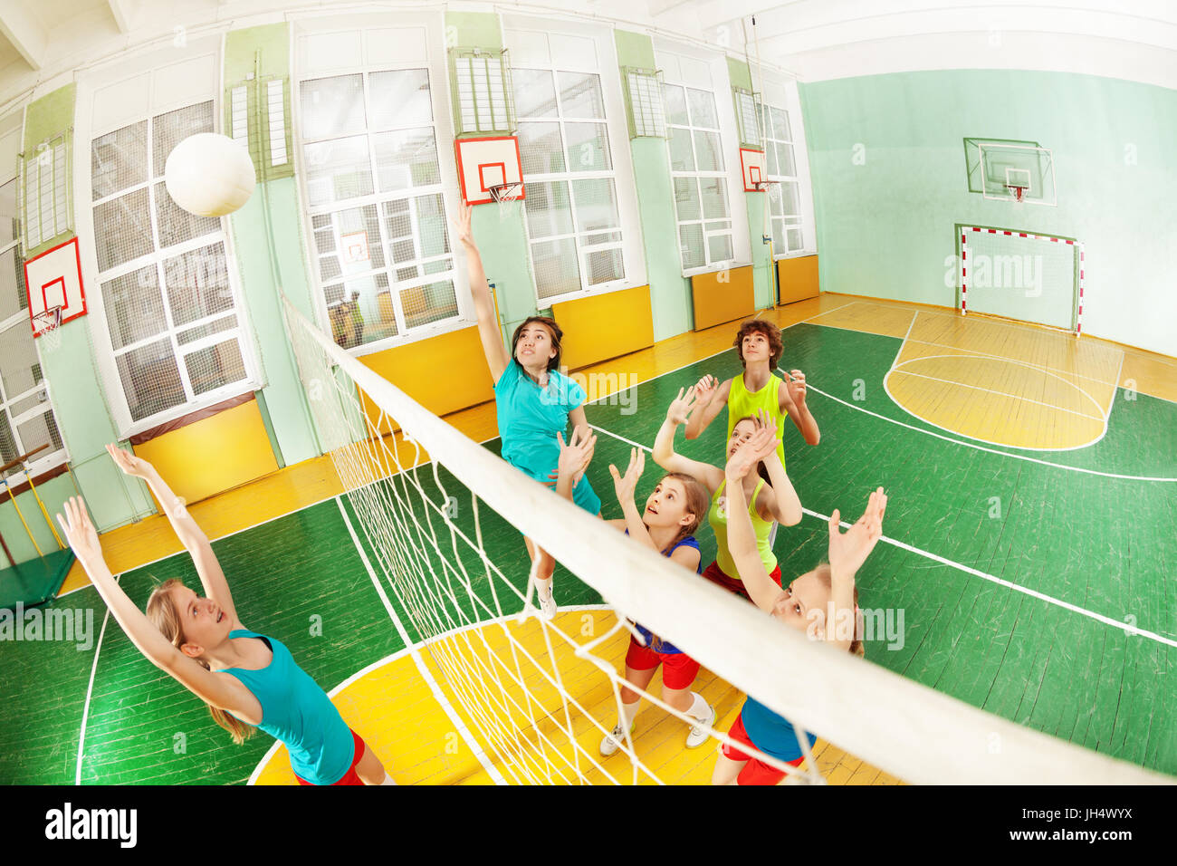 High angle view of teenagers playing volleyball in school gymnasium