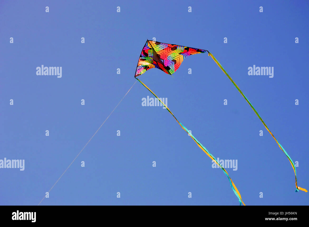 A multicolored kite streaming in the wind Stock Photo Alamy