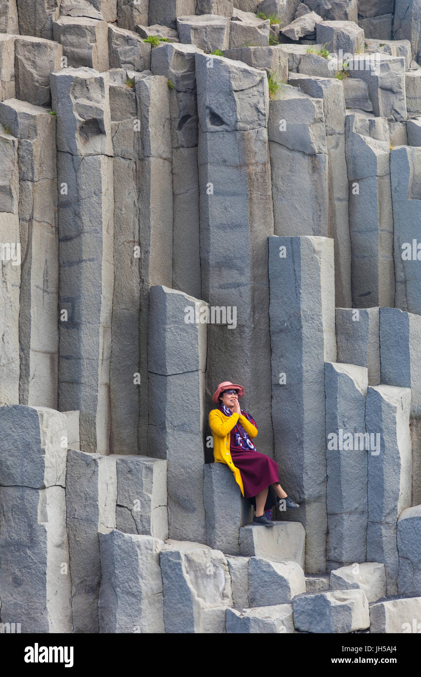 Tourist posing on the large basalt columns at Reynisfjara beach in Iceland Stock Photo