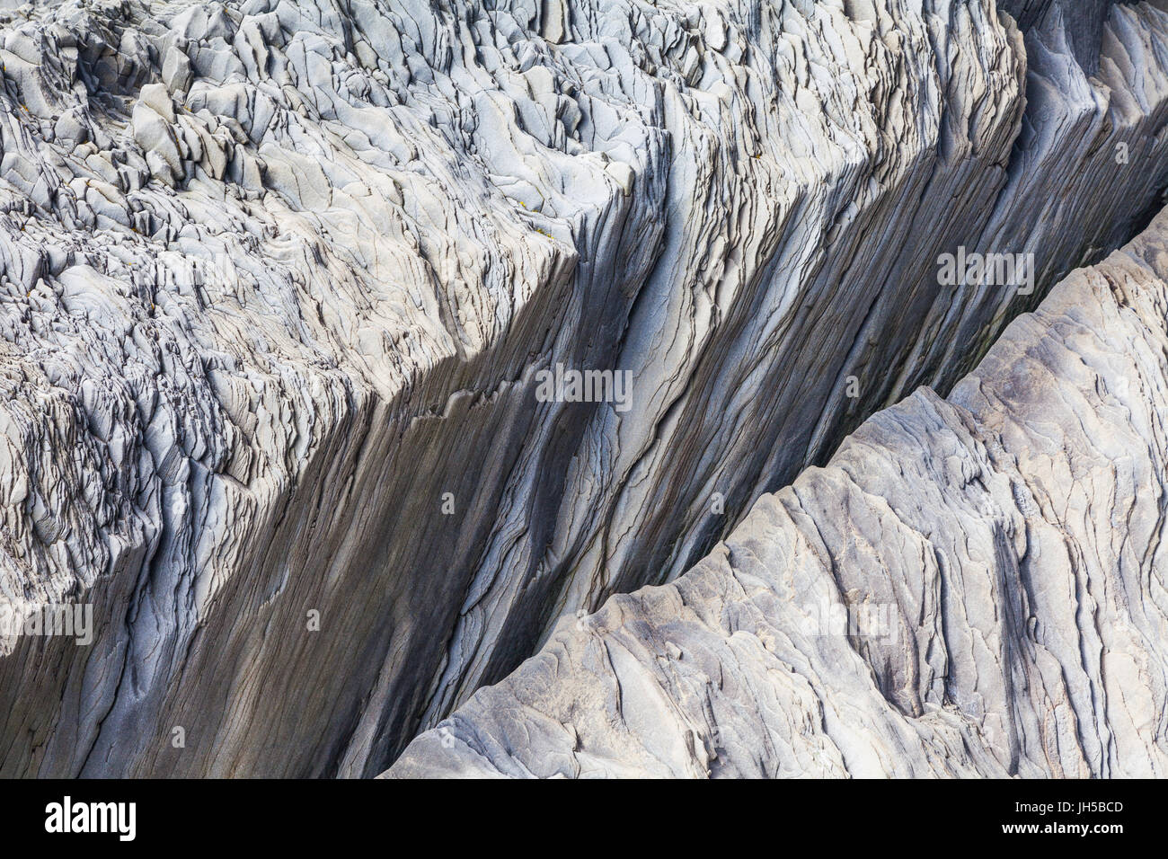 Shale-like rock depositions at the base of the cliffs on Reynisfjara beach in Iceland Stock Photo