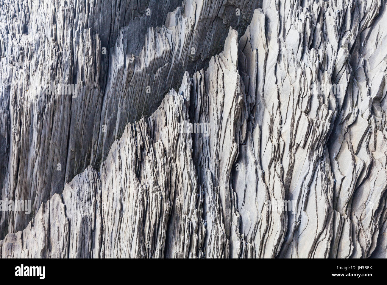 Shale-like rock depositions at the base of the cliffs on Reynisfjara beach in Iceland Stock Photo