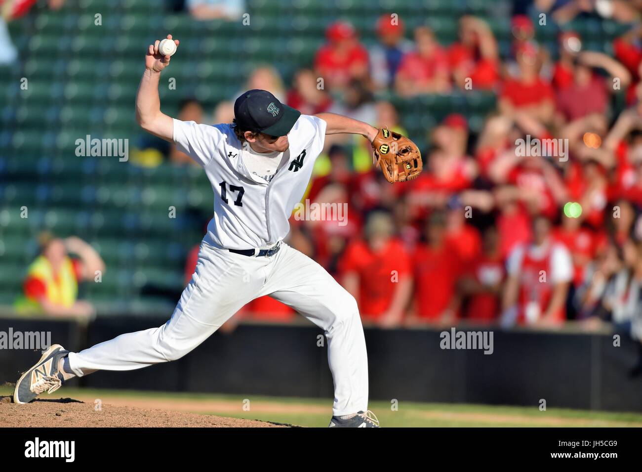 Pitcher delivering a pitch to an opposing hitter during a high school baseball game. USA. Stock Photo