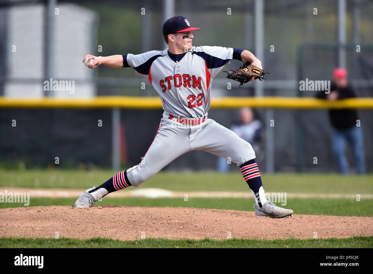 Pitcher delivering a pitch to an opposing hitter during a high school
