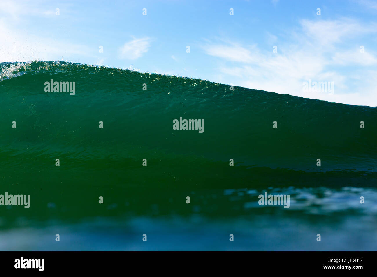 An abstract water angle of an emerald, powerful breaking wave on a bright summer day. Stock Photo