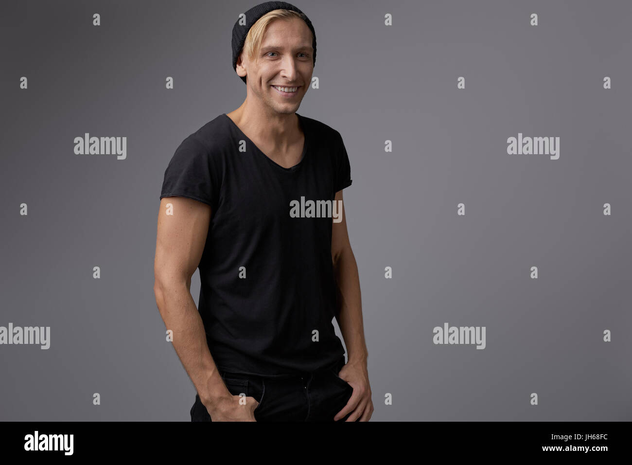 Portrait of a handsome young man smiling against gray background ...
