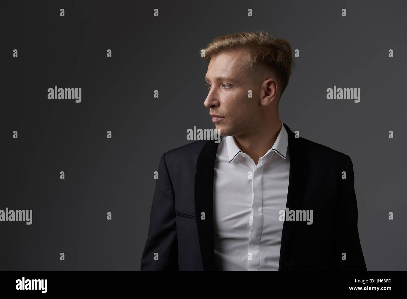Portrait of a handsome young man smiling against gray background ...