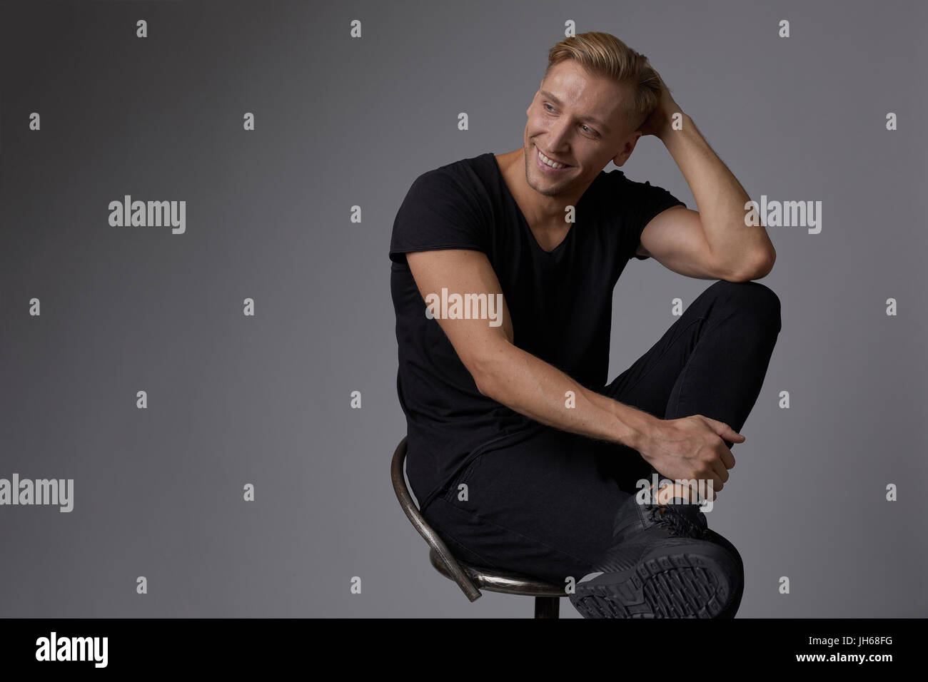 Portrait of a handsome young man smiling against gray background ...
