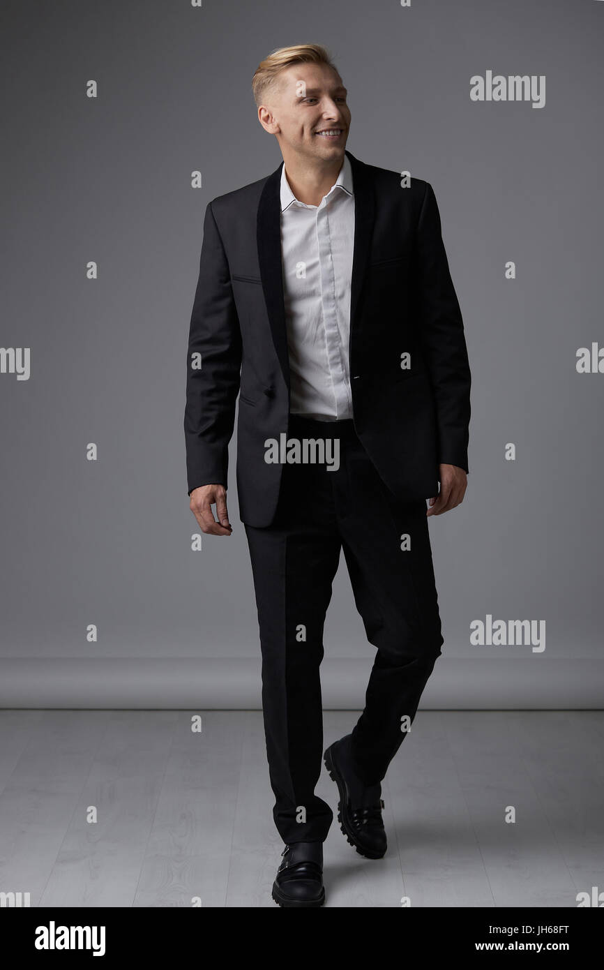 Portrait of a handsome young man smiling against gray background ...