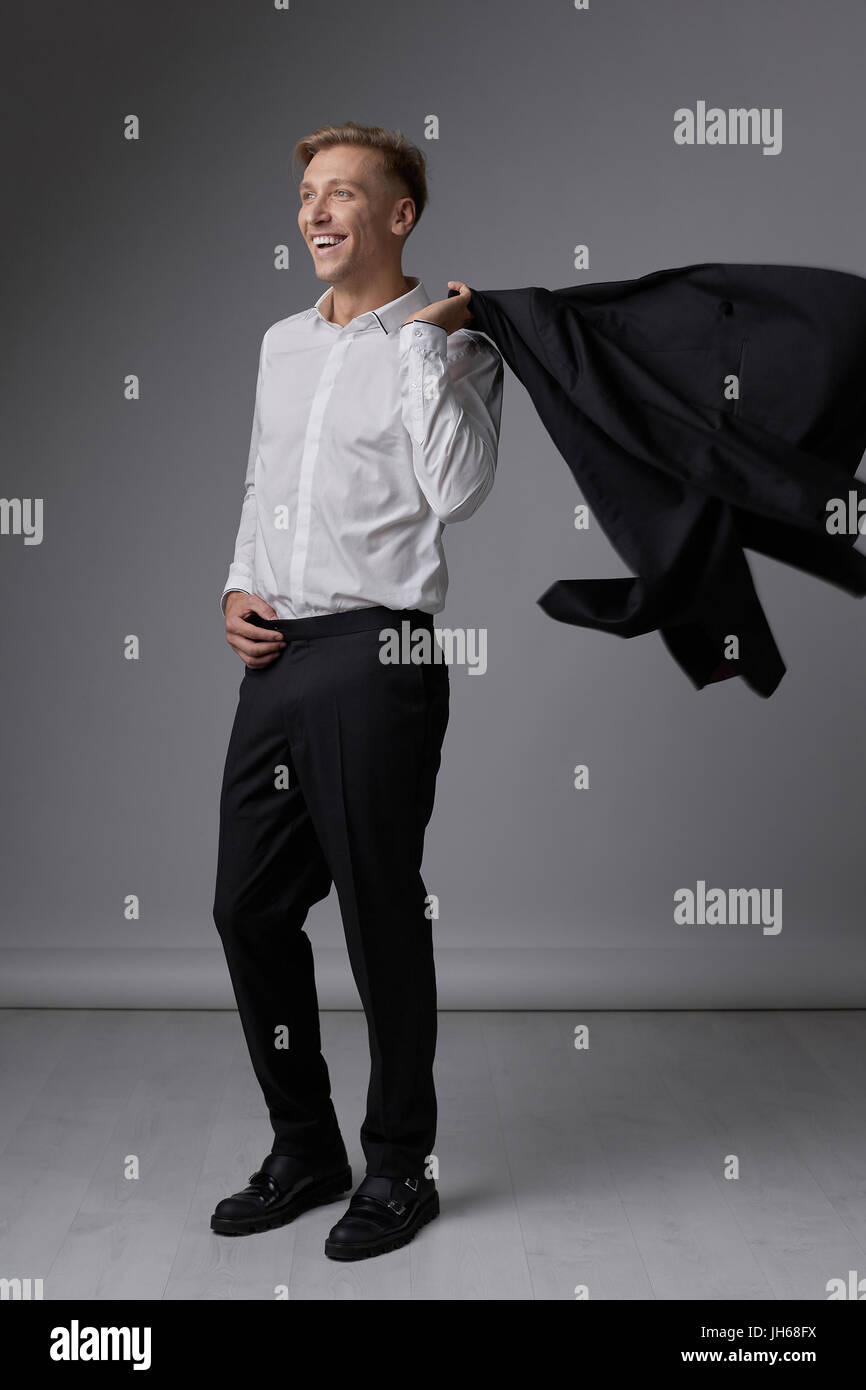 Portrait of a handsome young man smiling against gray background ...