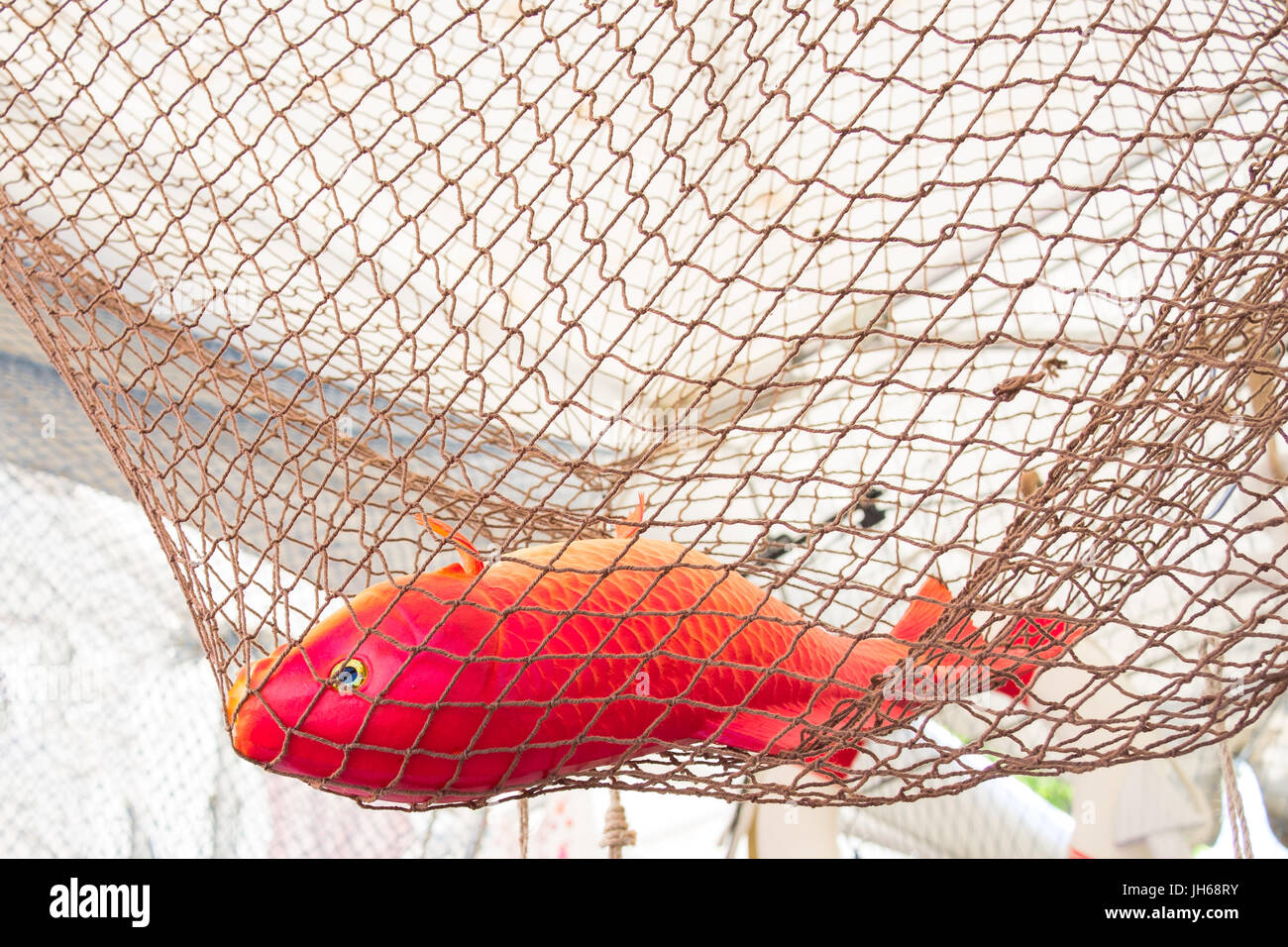 Red Orange plastic fish (goldfish, carp) in a rope fish net Stock Photo