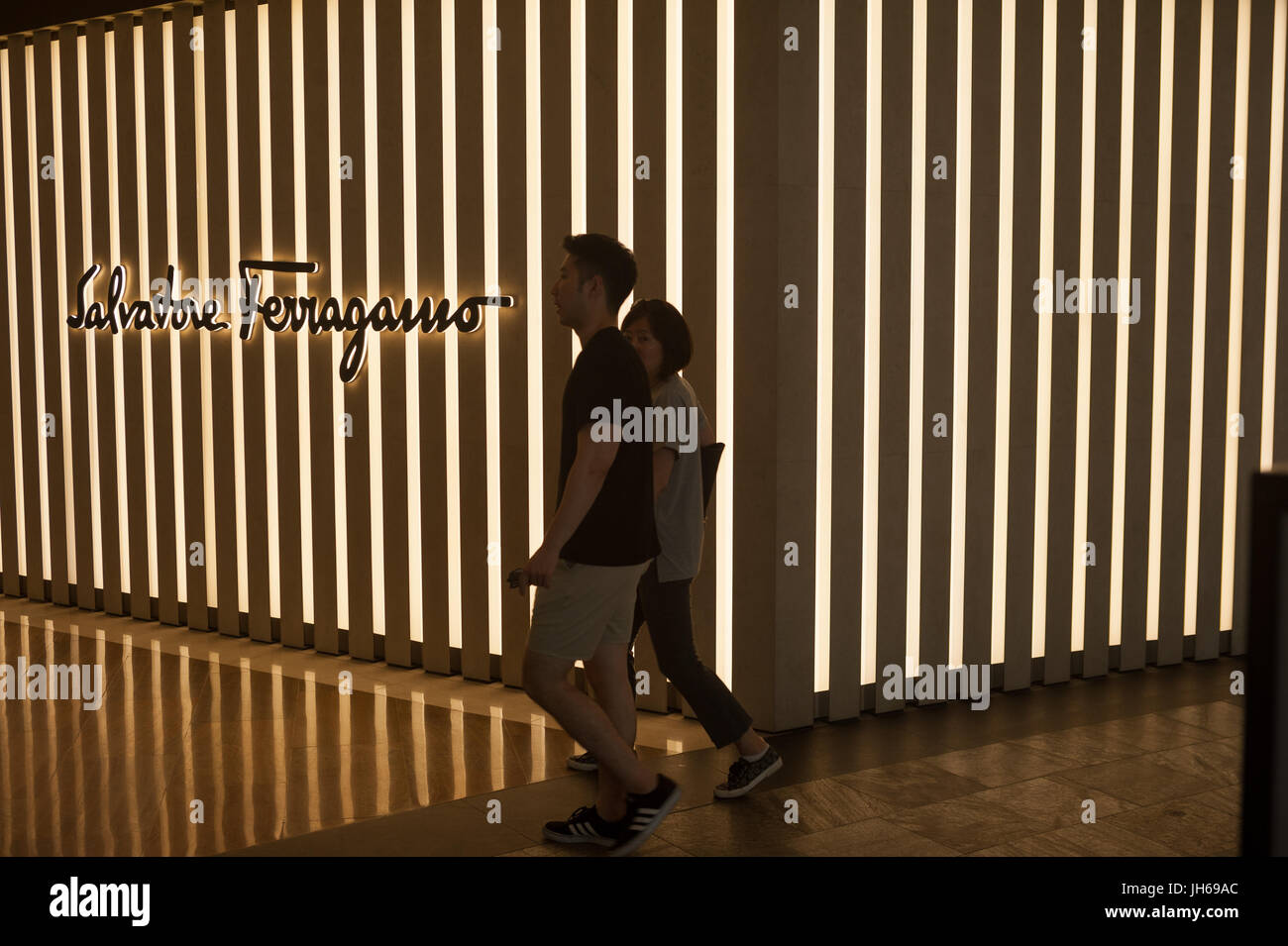 25.05.2017, Singapore, Republic of Singapore, Asia - A couple walks by a retail shop of the luxury brand Salvatore Ferragamo in 'The Shoppes' mall. Stock Photo