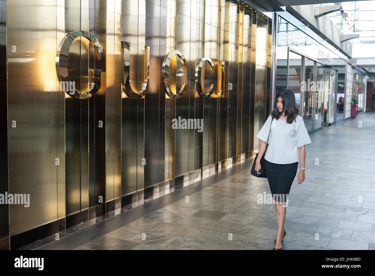 25.05.2017, Singapore, Republic of Singapore, Asia - A woman walks by a retail shop of the luxury brand Gucci in 'The Shoppes' shopping mall. Stock Photo