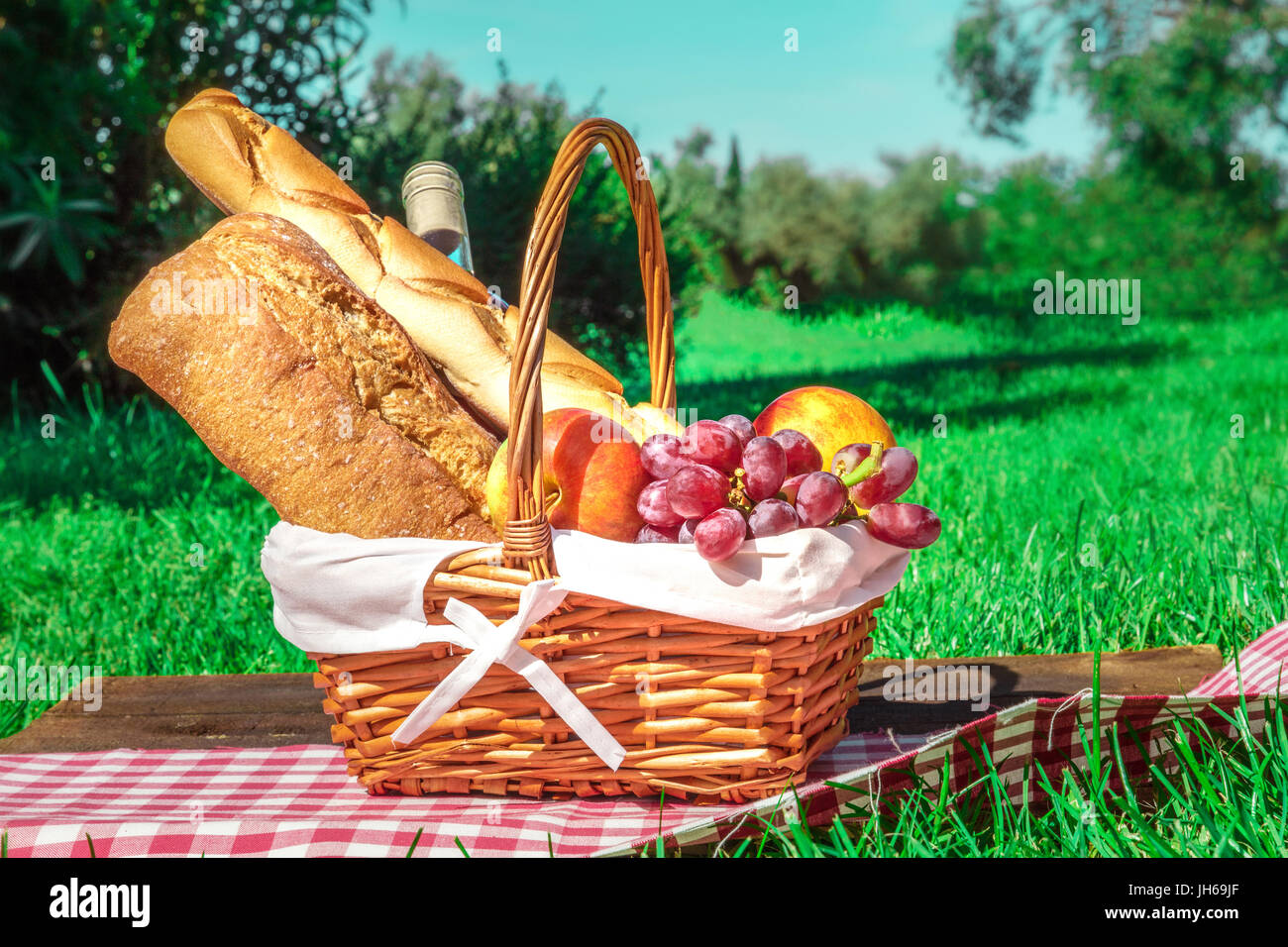 Picnic hamper with bread, fruit, and wine on green lawn Stock Photo Alamy