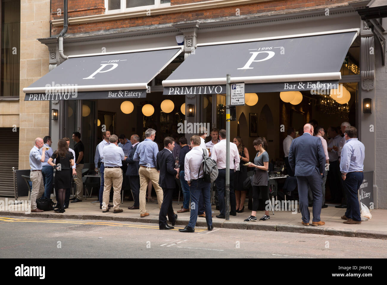 People standing drinking and eating on a pavement outside a Primitivo restaurant in Birmingham City Centre, UK Stock Photo
