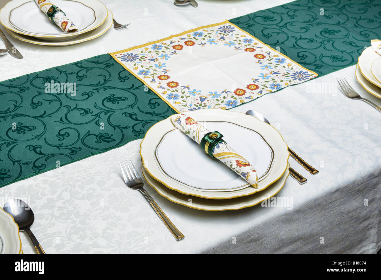 Dining table is set. Tablecloth, plates, knife, fork, spoon, napkin in the napkin ring. Selective focus. Stock Photo