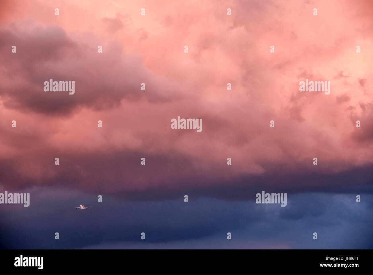 Commercial jet airliner taking off into heavy weather from Atlanta International Airport under ominous sunset-painted storm clouds. Stock Photo