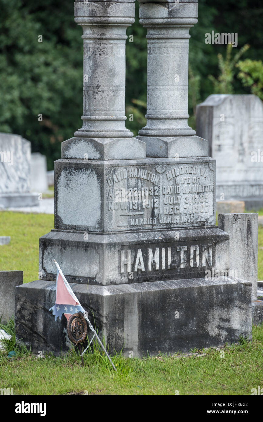 Tattered Confederate flag and Confederate Veteran maker next to gravestone memorial at Lawrenceville Historic Cemetery in Lawrenceville, Georgia, USA. Stock Photo