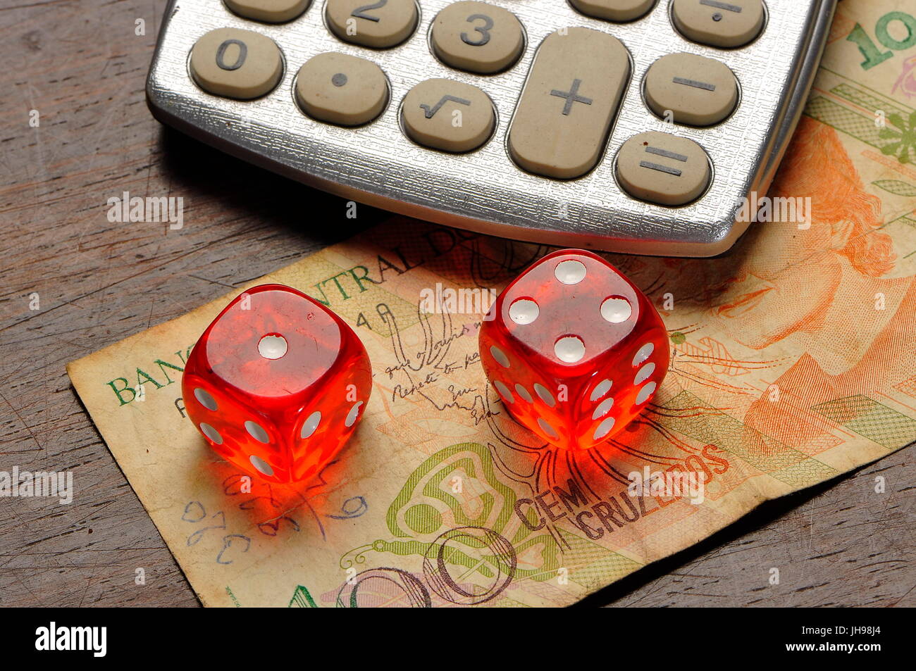 Red dices , calculator and old brazilian money note on a table Stock Photo