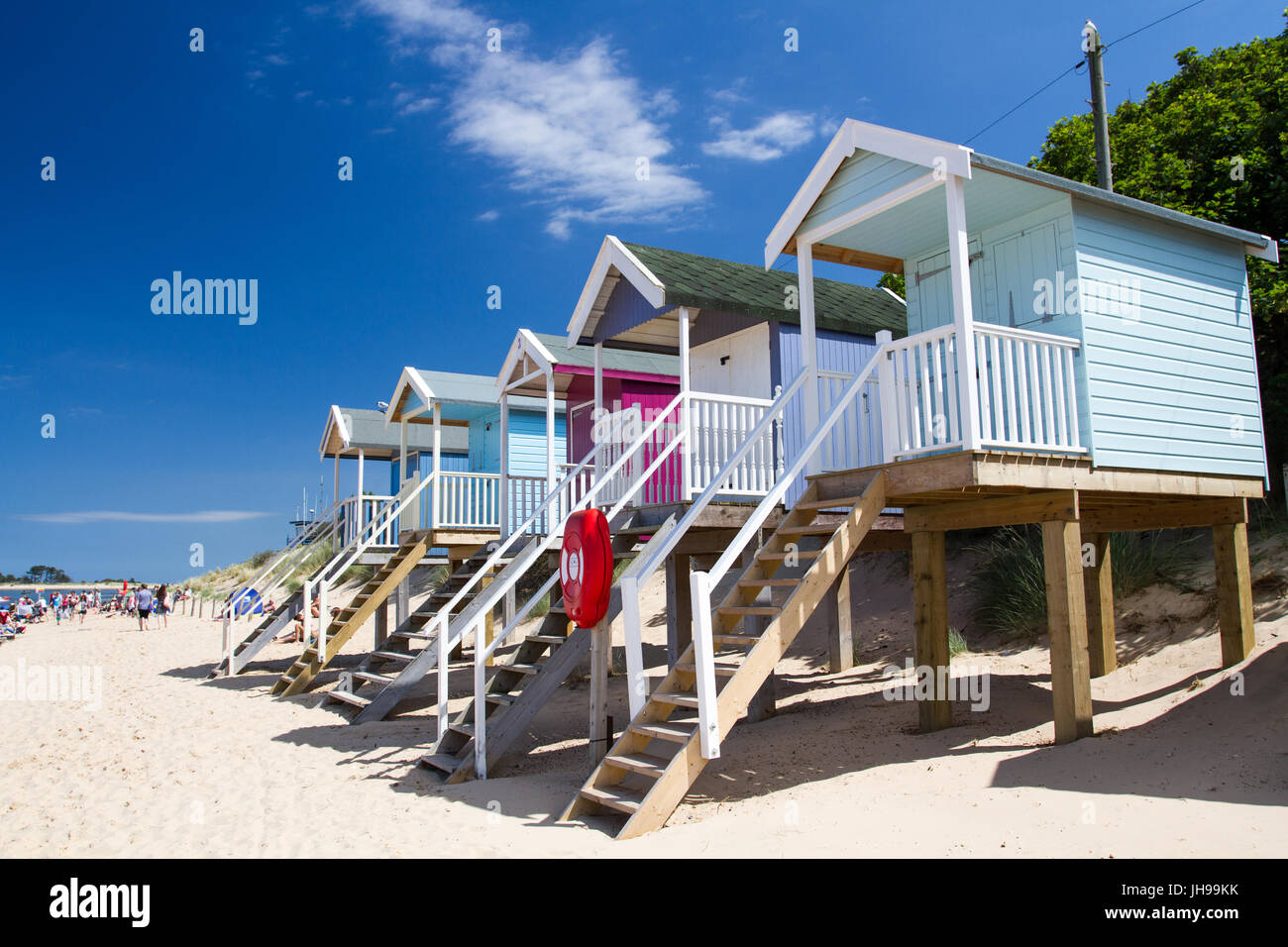 Rows of colourful beach huts on stilts on the sunny, sandy beach at