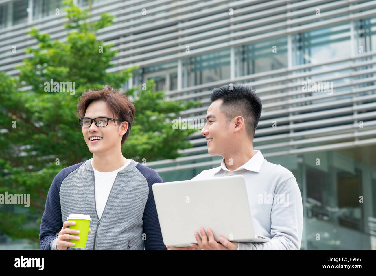 Two smiling young businessmen walking and talking in the city Stock ...