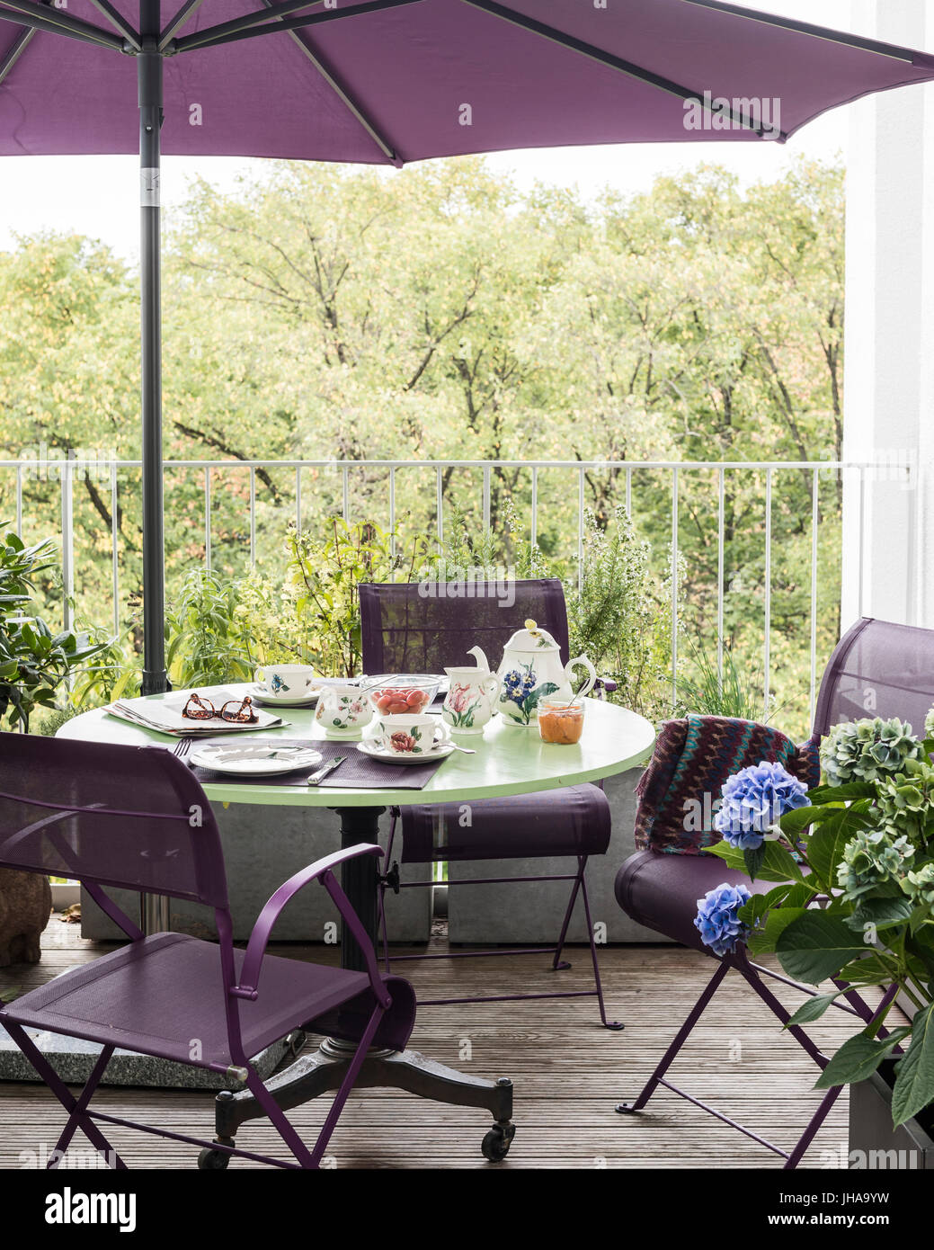 Purple chairs and parasol by table on deck Stock Photo