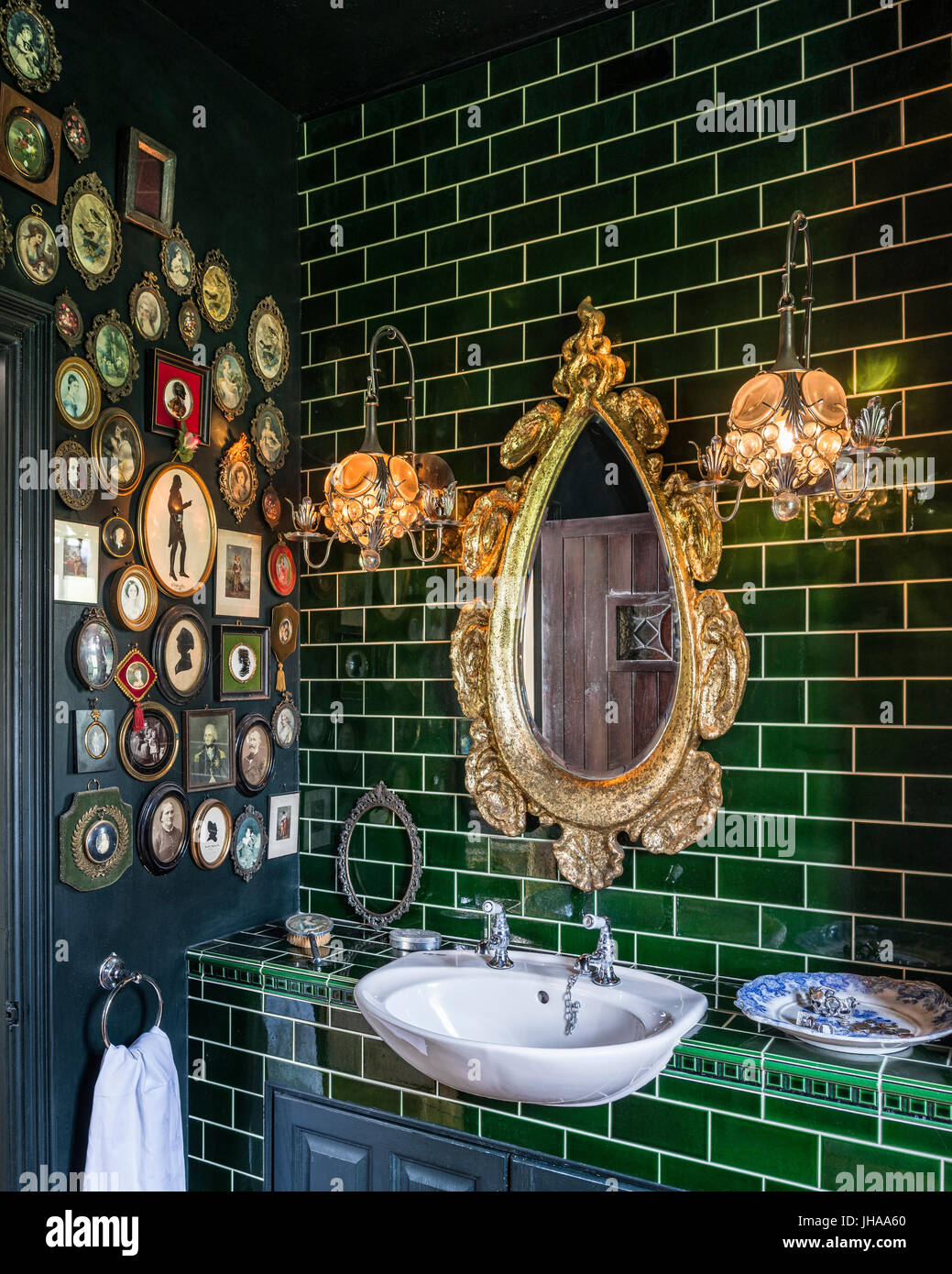 Gold mirror over washbasin with green tiles Stock Photo
