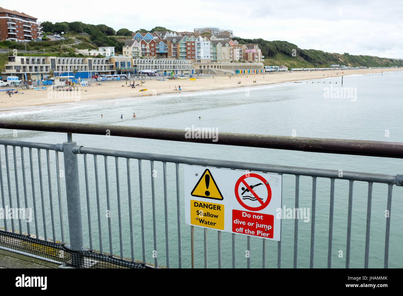 A sign warning people of shallow sea water and telling people not to dive or jump off the pier (Boscombe pier near Bournemouth in Dorset, England). Stock Photo